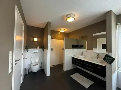 a bathroom with two sinks and a toilet at Groot vakantiehuis nabij Amsterdam inclusief jacuzzi in Zeewolde