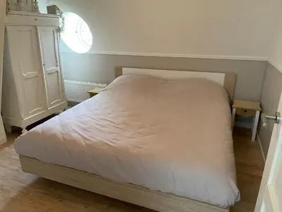 a bedroom with a white bed and a dresser at Veldhorst Apartments in Leiden