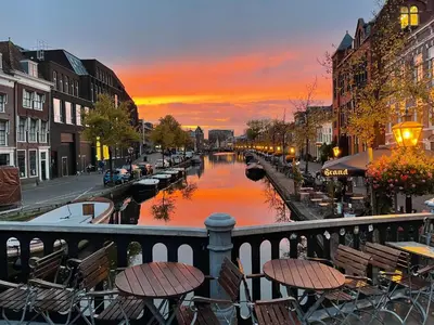 a view of a canal at sunset with tables and chairs at Veldhorst Apartments in Leiden