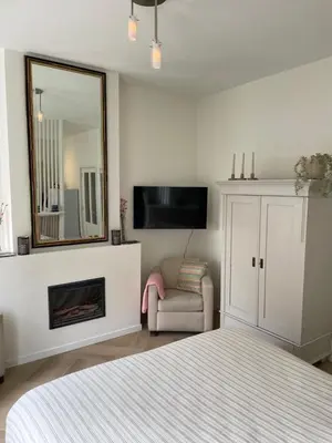 a bedroom with a bed and a mirror and a chair at Veldhorst Apartments in Leiden
