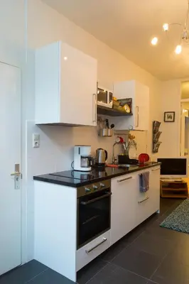a kitchen with white cabinets and a stove top oven at B&B Chez Cho in Utrecht