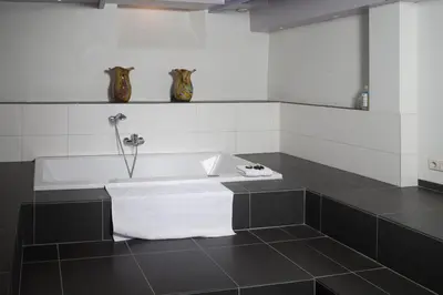 a bath tub in a bathroom with black and white tiles at B&B Chez Cho in Utrecht