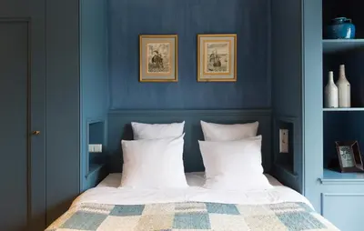 a bedroom with blue walls and a bed with white pillows at Suitehotel Posthoorn in Monnickendam