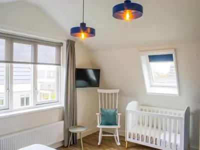 a baby room with a crib and two windows at Holiday Home in Noordwijk near the Beach in Noordwijk aan Zee