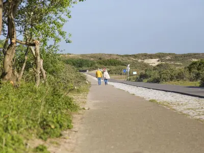 two people walking down a road at Holiday Home in Noordwijk near the Beach in Noordwijk aan Zee