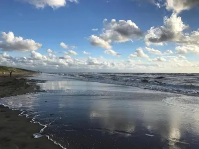 a beach with a body of water and clouds at Holiday Home in Noordwijk near the Beach in Noordwijk aan Zee