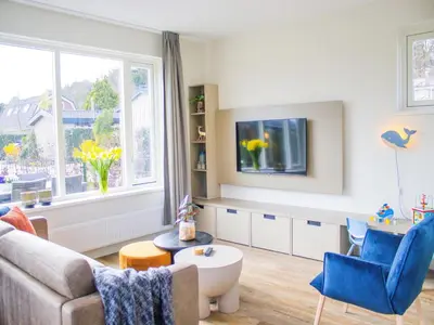 a living room with a couch and a tv at Holiday Home in Noordwijk near the Beach in Noordwijk aan Zee