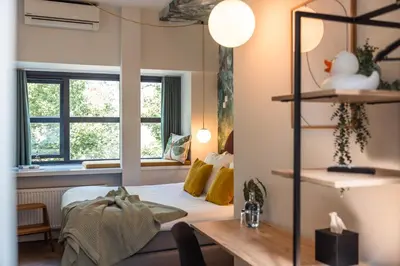 a bedroom with a bed and a desk and windows at Badhuis Hotel in Utrecht
