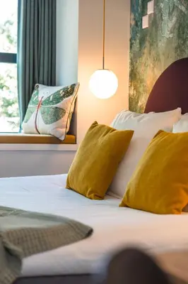 a bedroom with a bed with yellow pillows and a window at Badhuis Hotel in Utrecht