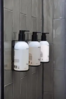 a group of three bottles of hair products on a wall at Badhuis Hotel in Utrecht