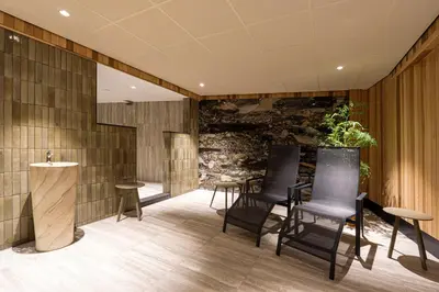 a lobby with chairs and a stone wall at Strandhotel Het Hoge Duin in Wijk aan Zee