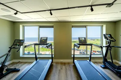a gym with three treadmills and a view of the ocean at Strandhotel Het Hoge Duin in Wijk aan Zee