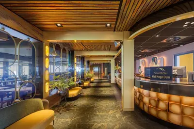 a corridor of a restaurant with a row of seats at Strandhotel Het Hoge Duin in Wijk aan Zee
