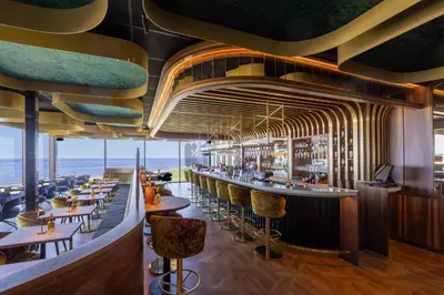 a restaurant with a bar with a view of the ocean at Strandhotel Het Hoge Duin in Wijk aan Zee
