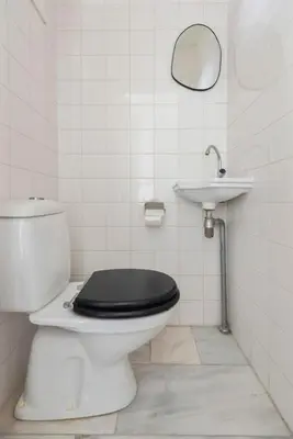 a bathroom with a toilet with a black seat and a sink at De Schelp 58 in Zandvoort