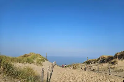 people walking down a sandy path to the beach at De Schelp 58 in Zandvoort