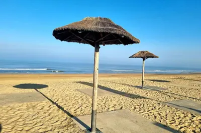two straw umbrellas on a sandy beach at De Schelp 58 in Zandvoort