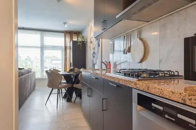 a kitchen with a stove top oven next to a table at De Schelp 58 in Zandvoort
