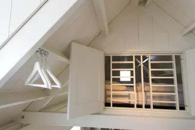 a attic room with a window and a ladder at Waterland Vakantiehuis in Monnickendam