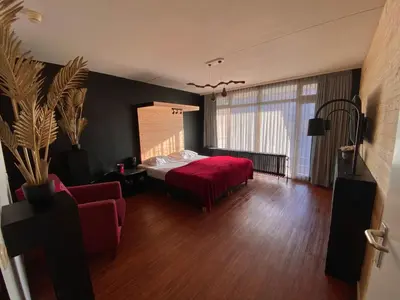 a bedroom with a red bed and a red couch at Anno in Almere
