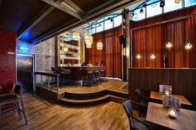 a restaurant with a bar with tables and chairs at Anno in Almere