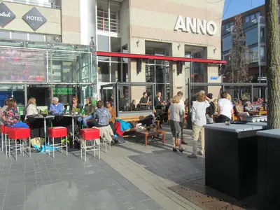 a group of people sitting at tables in front of a building at Anno in Almere