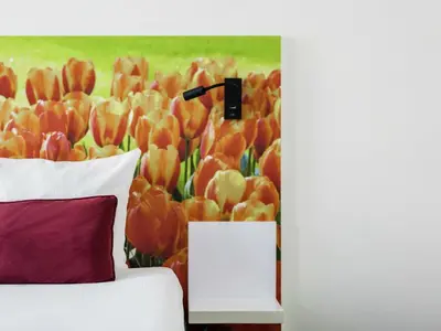 a bedroom with a bed with a painting of tulips at ibis Styles Amsterdam City in Amsterdam
