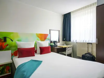 a hotel room with a large white bed with red pillows at ibis Styles Amsterdam City in Amsterdam