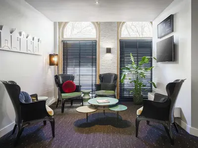 a waiting room with chairs and a table and a tv at ibis Styles Amsterdam City in Amsterdam