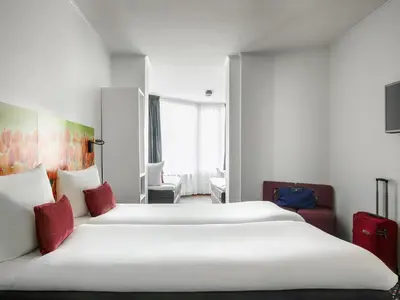 a hotel room with two beds with red pillows at ibis Styles Amsterdam City in Amsterdam