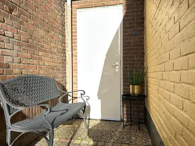 a bench sitting next to a brick wall with a door at Lovely tiny house in Zandvoort