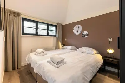 two twin beds in a bedroom with a window at Dormio Park Scorleduyn in Schoorl