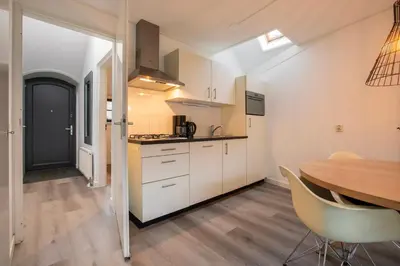 a kitchen with white cabinets and a wooden table at Dormio Park Scorleduyn in Schoorl