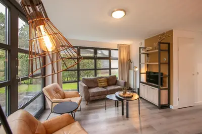 a living room with a couch and a table at Dormio Park Scorleduyn in Schoorl