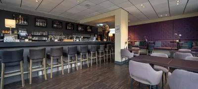 a bar in a restaurant with chairs and a counter at Fletcher Hotel Restaurant Zeeduin in Wijk aan Zee