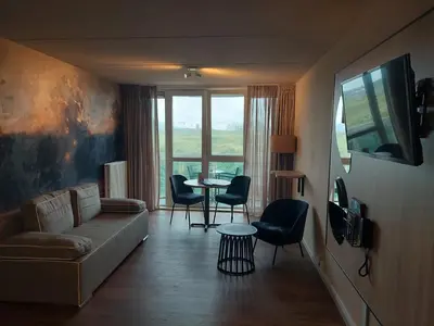 a living room with a couch and a table with chairs at Fletcher Hotel Restaurant Zeeduin in Wijk aan Zee