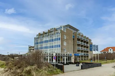 a large building with blue windows on a street at Fletcher Hotel Restaurant Zeeduin in Wijk aan Zee