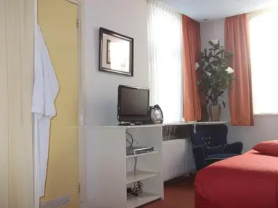 a bedroom with a bed and a tv on a shelf at Hotel Hoogland Zandvoort aan Zee in Zandvoort