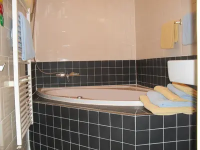 a bathroom with a bath tub with blue tiles at Hotel Hoogland Zandvoort aan Zee in Zandvoort