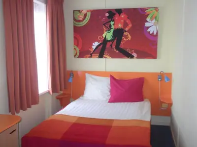 a bedroom with a colorful bed with a painting on the wall at Hotel Hoogland Zandvoort aan Zee in Zandvoort