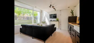 a living room with a couch and a large window at Quiet Garden Room Amsterdam West - by Peter in Amsterdam