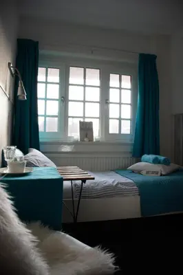 a bedroom with blue curtains and a bed and a table at Bed & Breakfast Hotel Zandvoort in Zandvoort