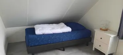 a small bed with a blue blanket and a night stand at De Strandwielen in Sint Maarten