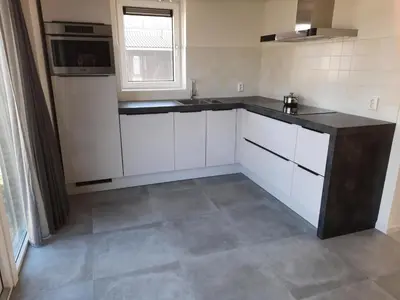a kitchen with white cabinets and a sink and a window at De Strandwielen in Sint Maarten