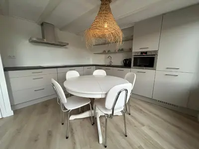a white kitchen with a white table and chairs at Lakeside Cottage De Rijd in Nieuwe-Niedorp