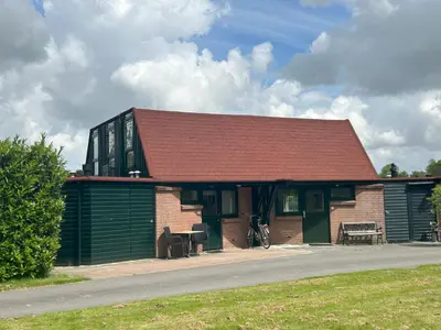 a small building with a red roof and a house at Lakeside Cottage De Rijd in Nieuwe-Niedorp