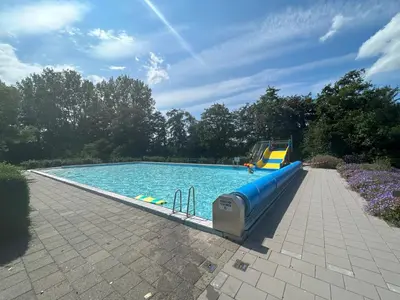 a large swimming pool with a blue slide in the middle at Lakeside Cottage De Rijd in Nieuwe-Niedorp