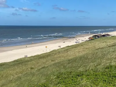 a beach with people on the sand and the ocean at Lakeside Cottage De Rijd in Nieuwe-Niedorp