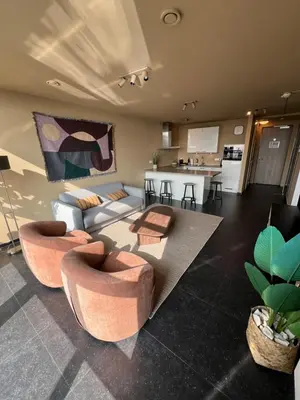 a living room with a couch and chairs and a kitchen at Cala Bassa Beach Boutique Apartments - Beach View in Overveen
