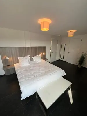 a bedroom with a large white bed and a bench at Cala Bassa Beach Boutique Apartments - Beach View in Overveen